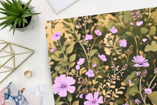 Green foliage and light purple chicory illustration wildflower desk mat from Spruce and Heron on a desktop.