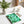 A spiral notebook with a green fern leaf pattern on the cover sits on a white desk next to a potted fern, a candle, and pens - Fern Spiral Notebook from Spruce and Heron.