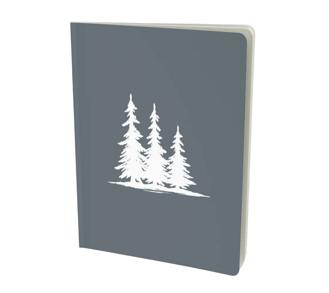 A dark gray hardcover notebook featuring a white line art illustration of four pine trees on the front cover, shown at a three-quarter angle against a light gray background - Spruce Trees Notebook - Minimalist in Charcoal from Spruce and Heron. 