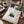 A natural white canvas tote bag with a black pine tree graphic sits on a wooden table, styled with books, a mug, and a green patterned pouch - Spruce Trees Tote Bag from Spruce and Heron.