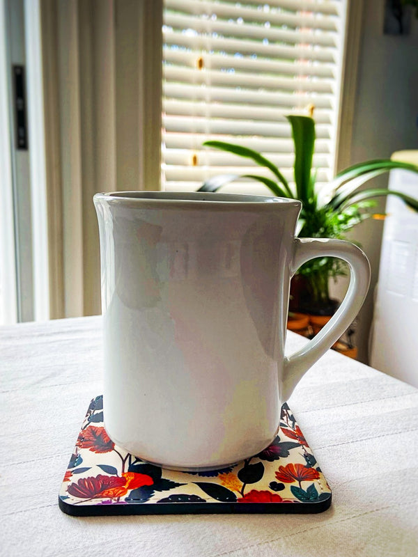 Pretty vintage summer floral coaster under a white cup in a kitchen setting.